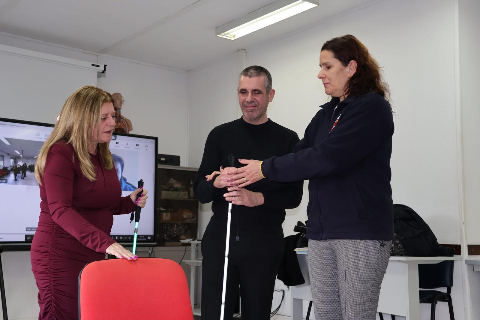 A Teresa mostra como a Ana deve indicar a cadeira ao Ricardo.